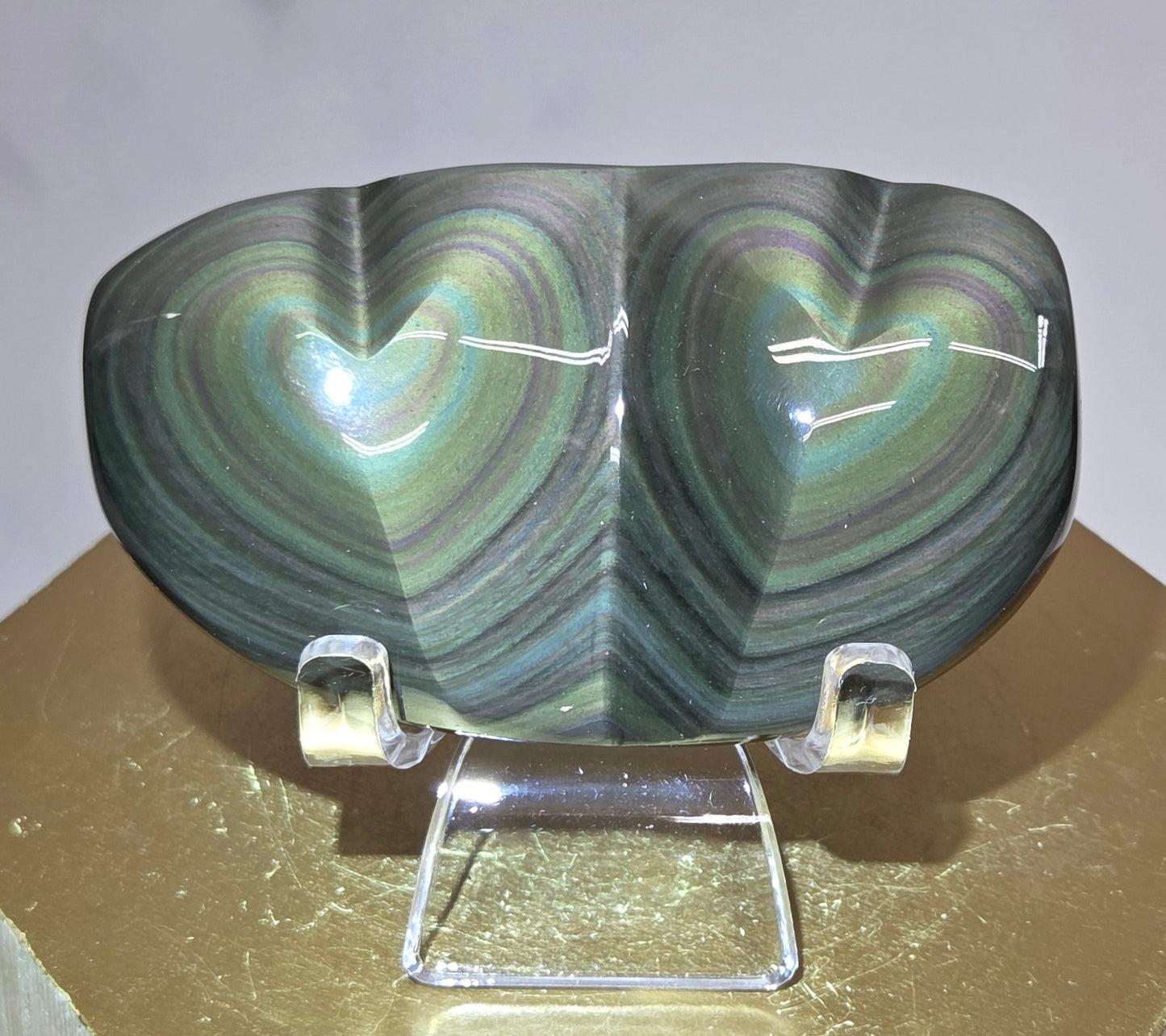 Obsidian carving on an acrylic stand against a neutral background