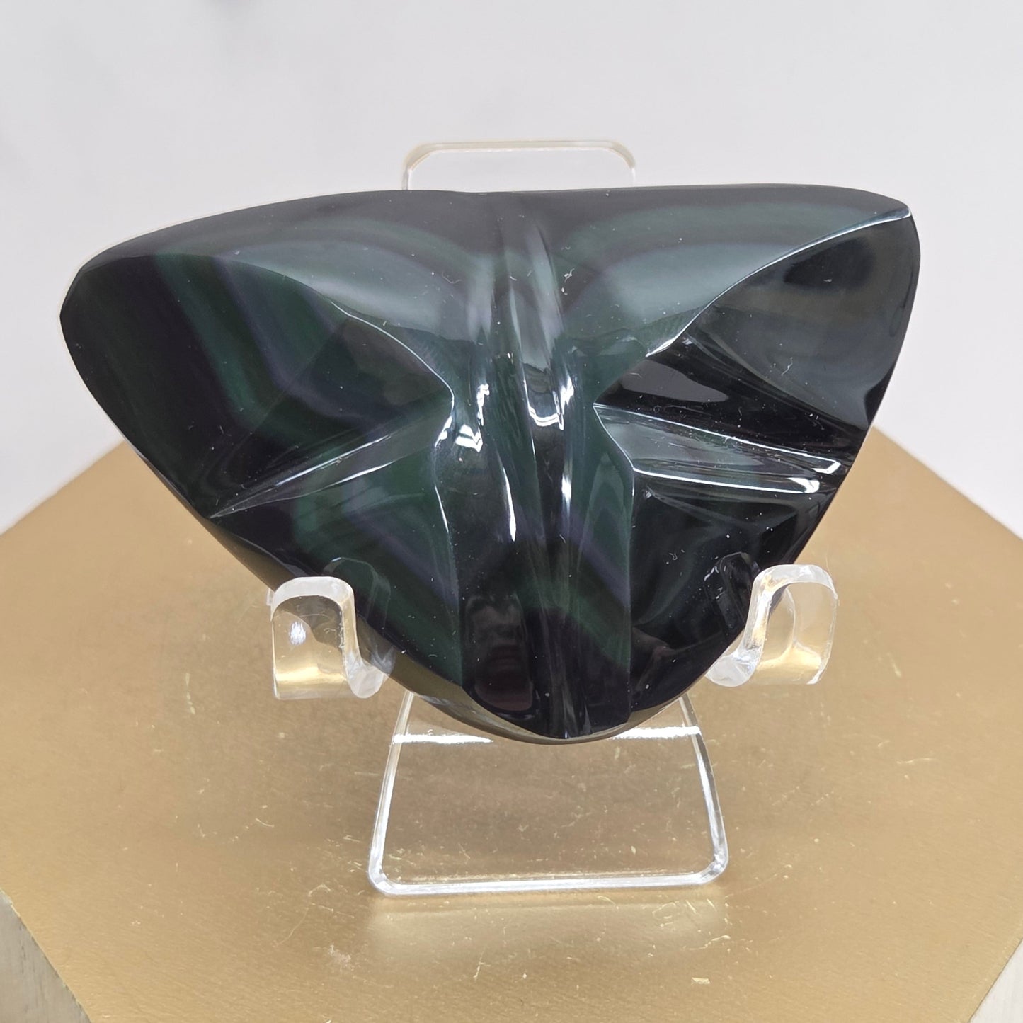 Obsidian carving on an acrylic stand against a neutral background