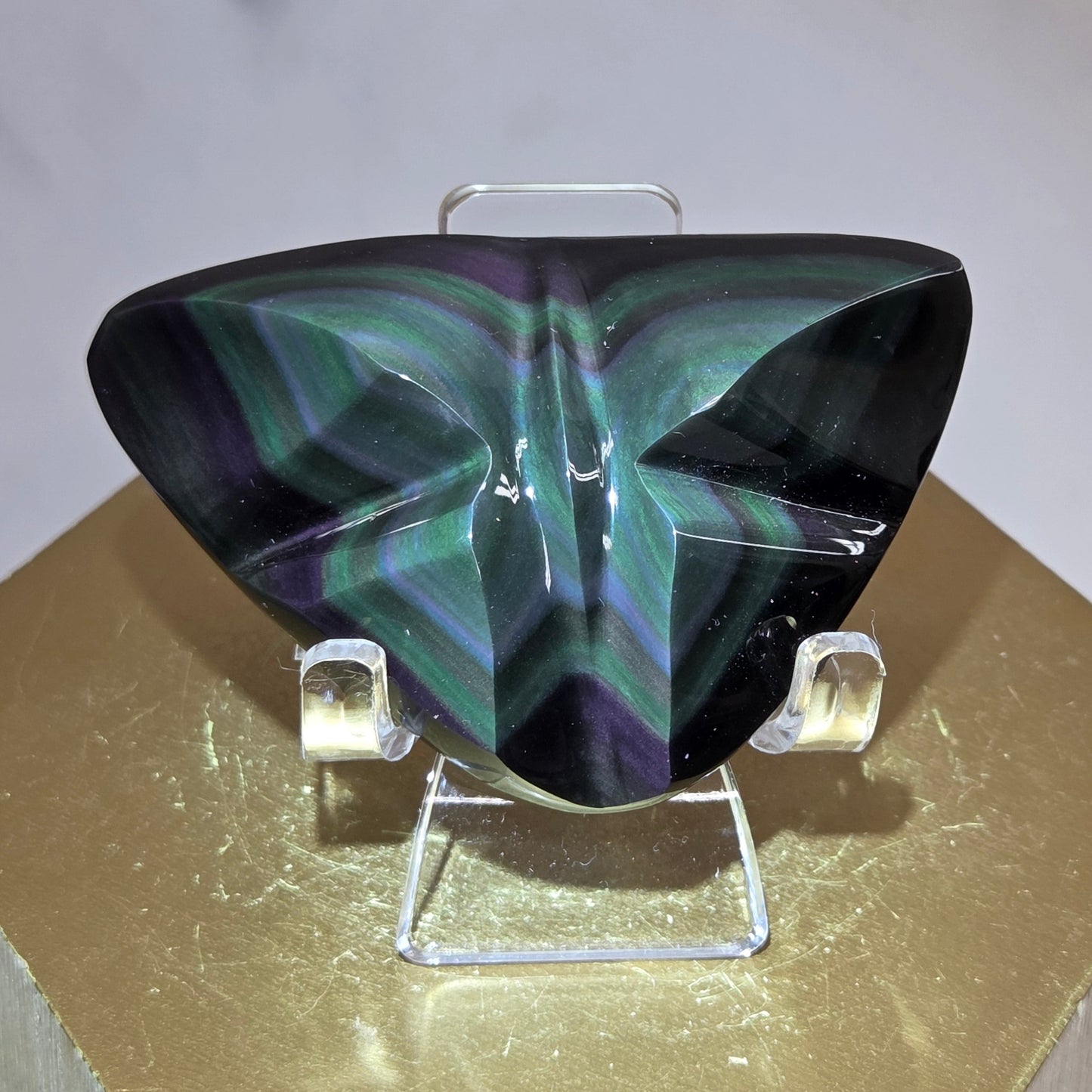 Obsidian carving on an acrylic stand against a neutral background