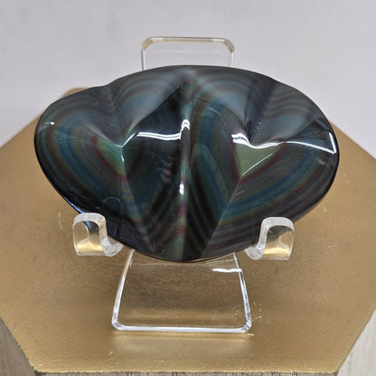 Obsidian carving on an acrylic stand against a neutral background