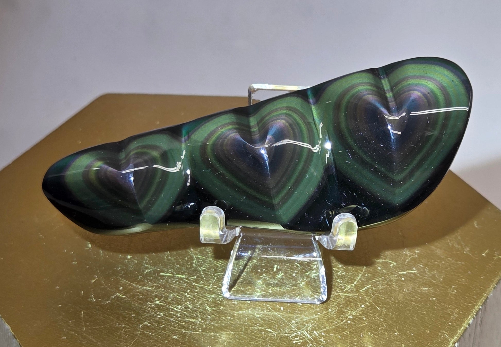 Obsidian carving on an acrylic stand against a neutral background