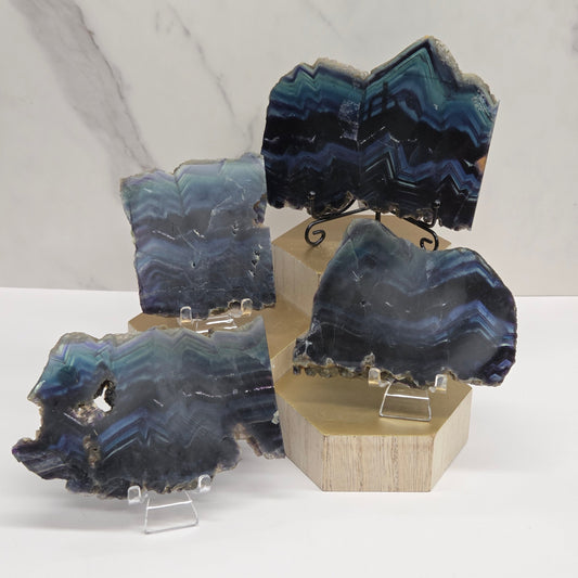 Banded fluorite slabs on a wooden stand against a neutral background