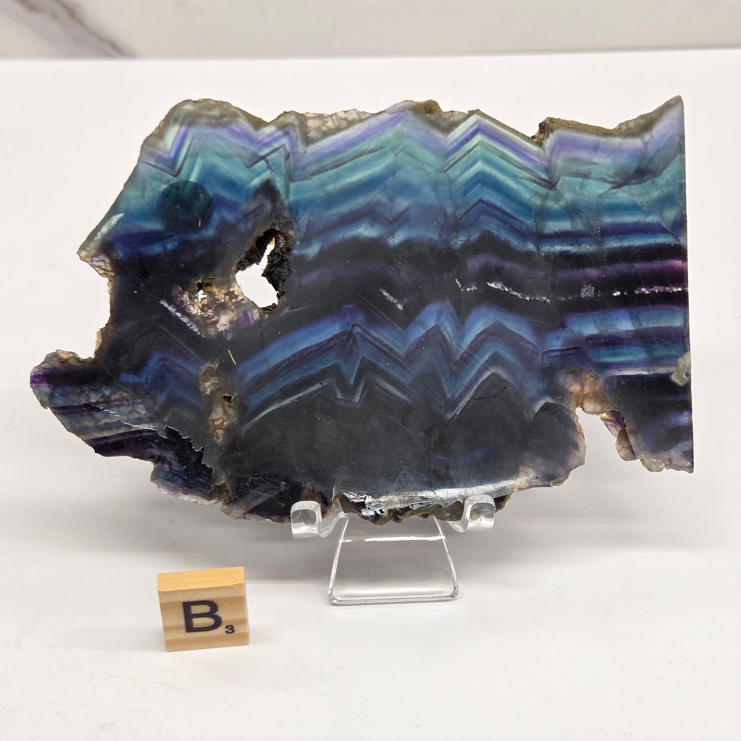 Banded fluorite slabs on a stand against a neutral background