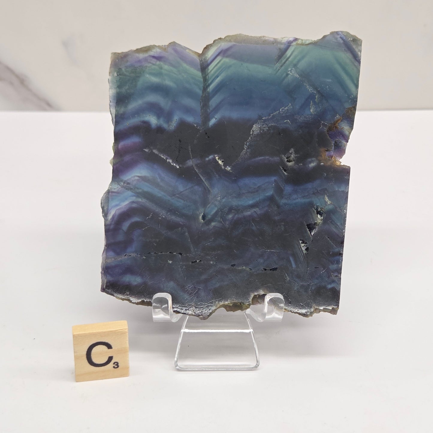 Banded fluorite slabs on a stand against a neutral background