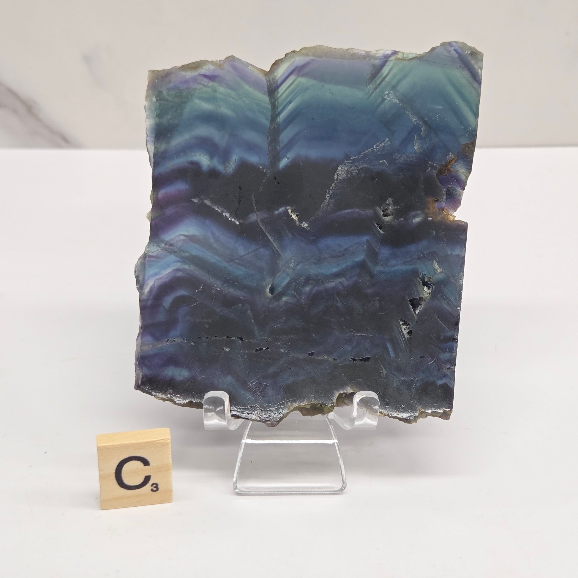 Banded fluorite slabs on a stand against a neutral background