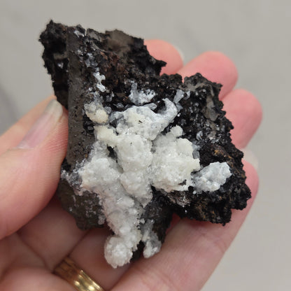 Hand holding a crystal specimen against a neutral background