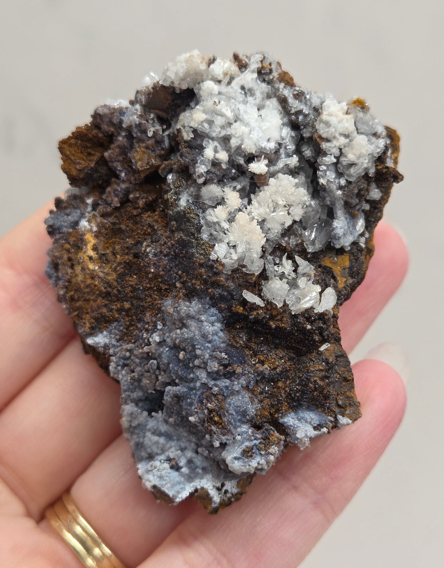 Hand holding a crystal rock with a neutral background