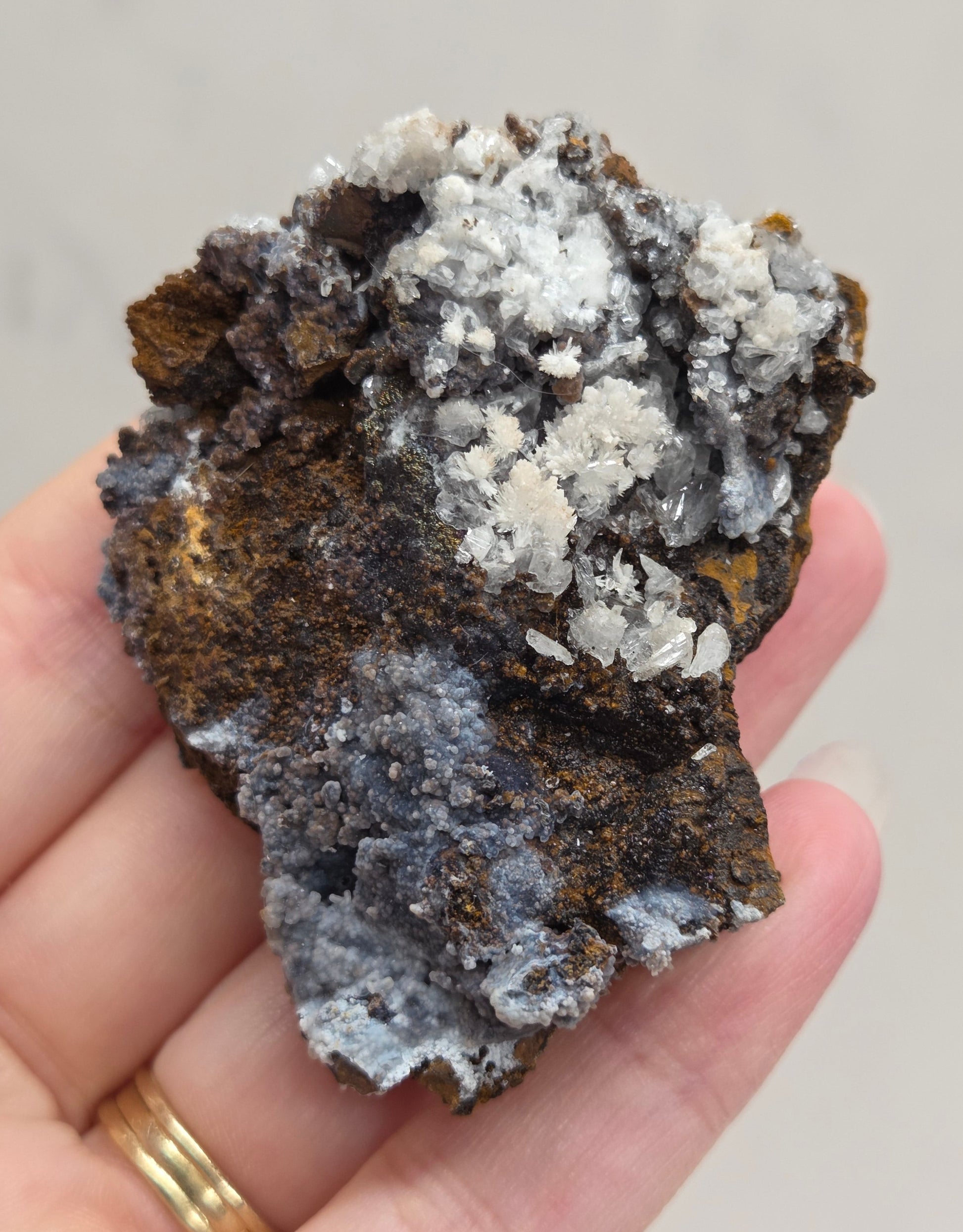 Hand holding a crystal rock with a neutral background