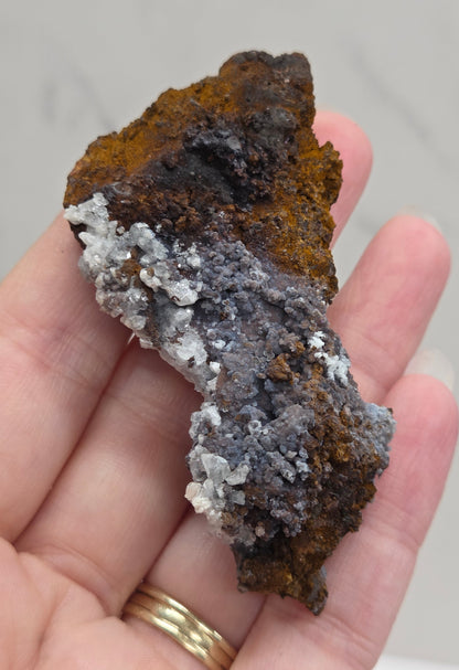 Hand holding a mineral specimen with a neutral background