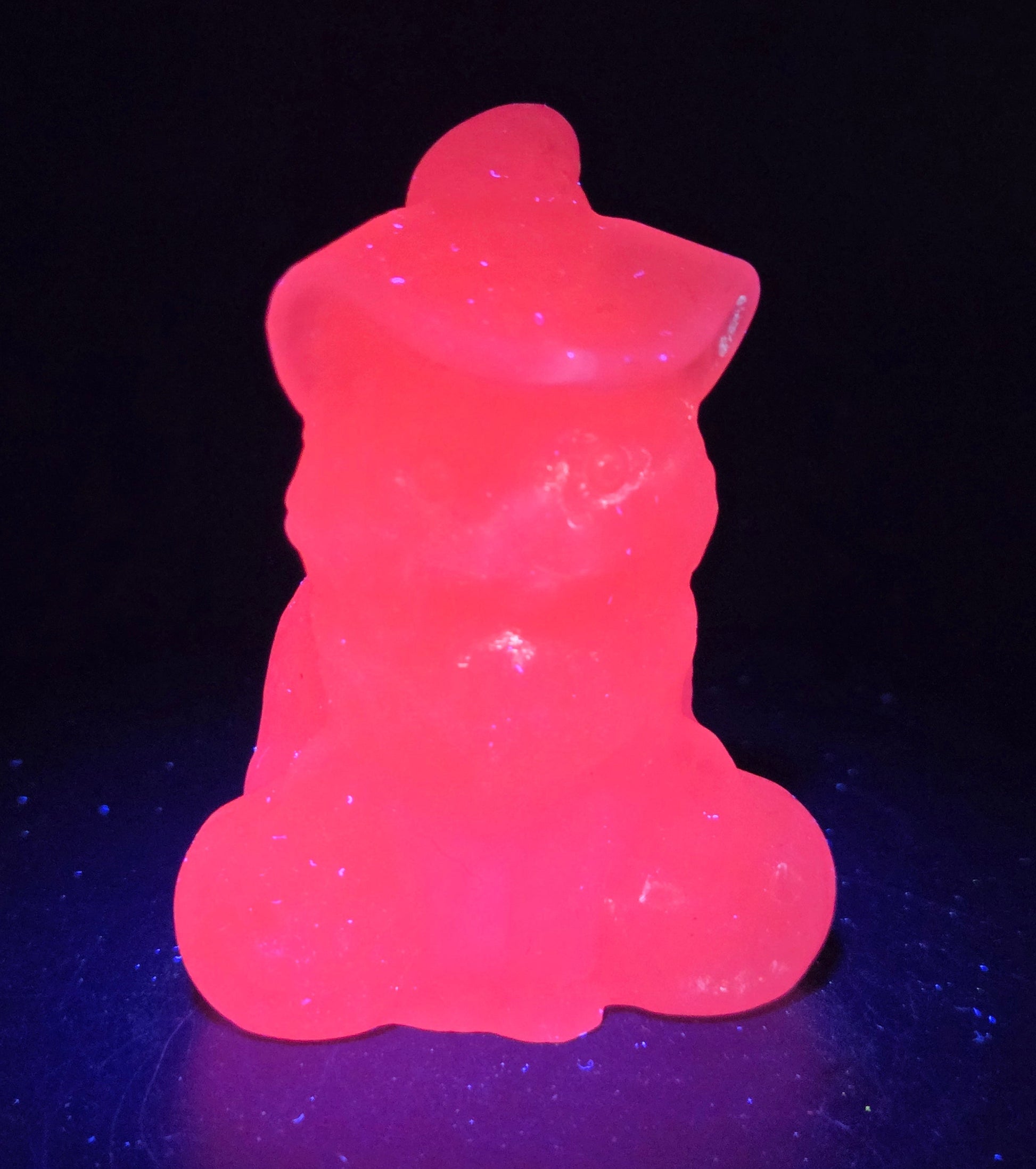 Glowing pink cat carving with pumpkins on a reflective black surface with a dark background