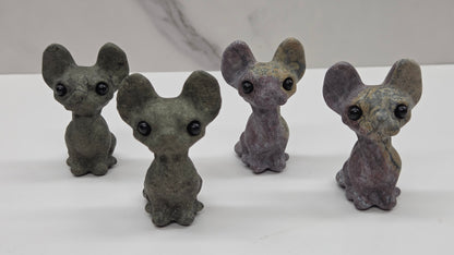 Four gray cat-like figurines on a white surface with a light gray background