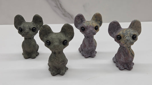 Four gray cat-like figurines on a white surface with a light gray background