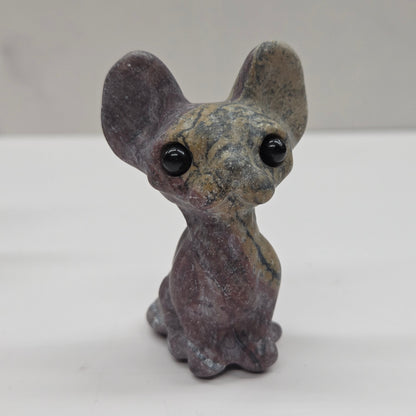 Small gray figurine of a cat with large eyes on a white surface