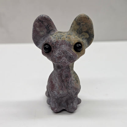 Small gray figurine of a cat with large eyes on a white surface