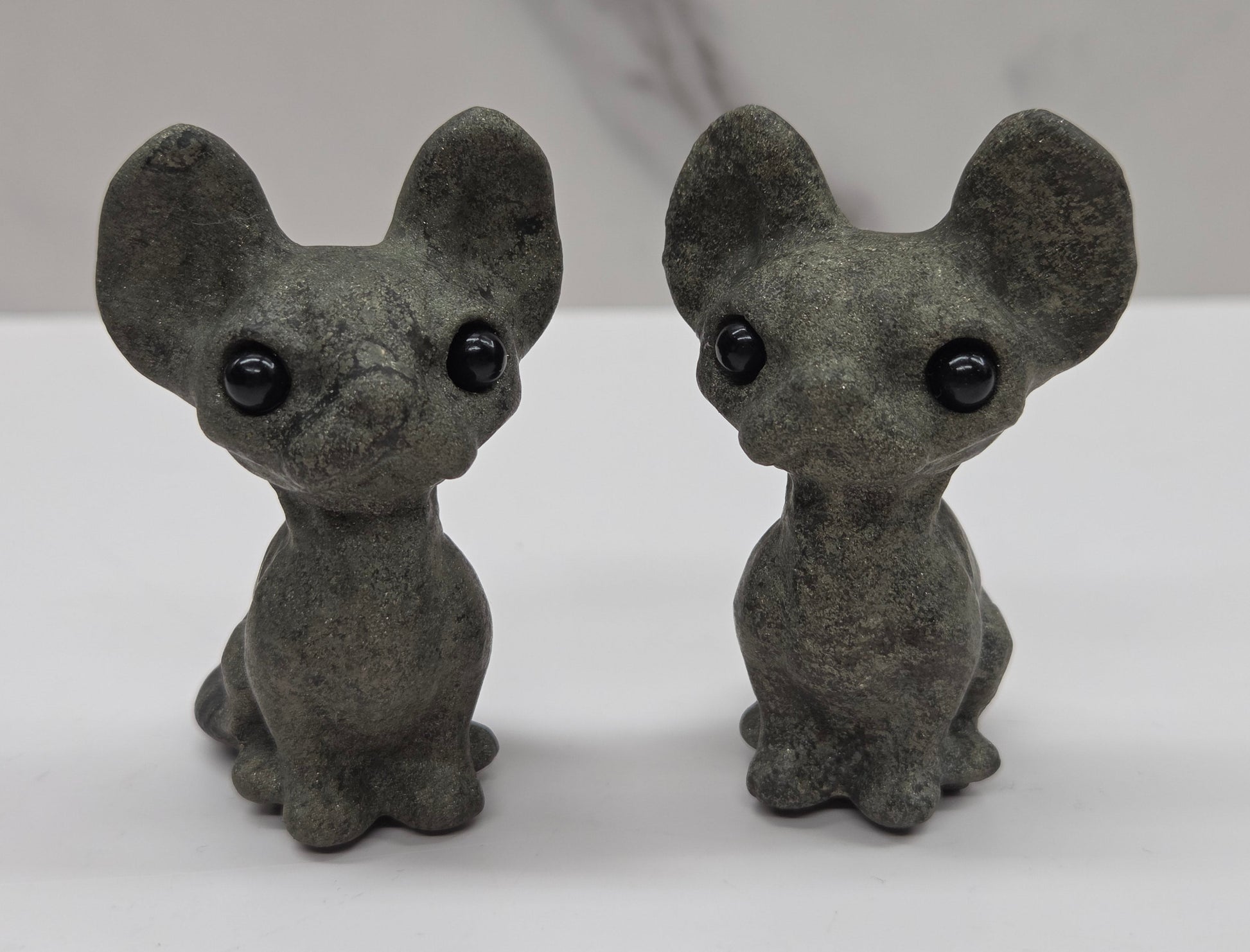 Small gray figurine of a cat with large eyes on a white surface