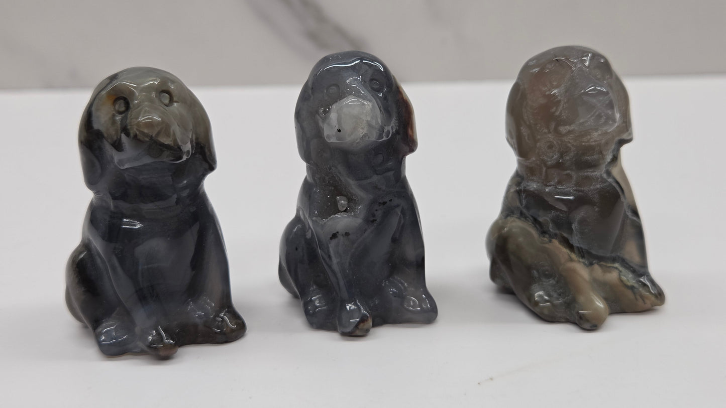 Three stone dog figurines on a white surface with a gray background