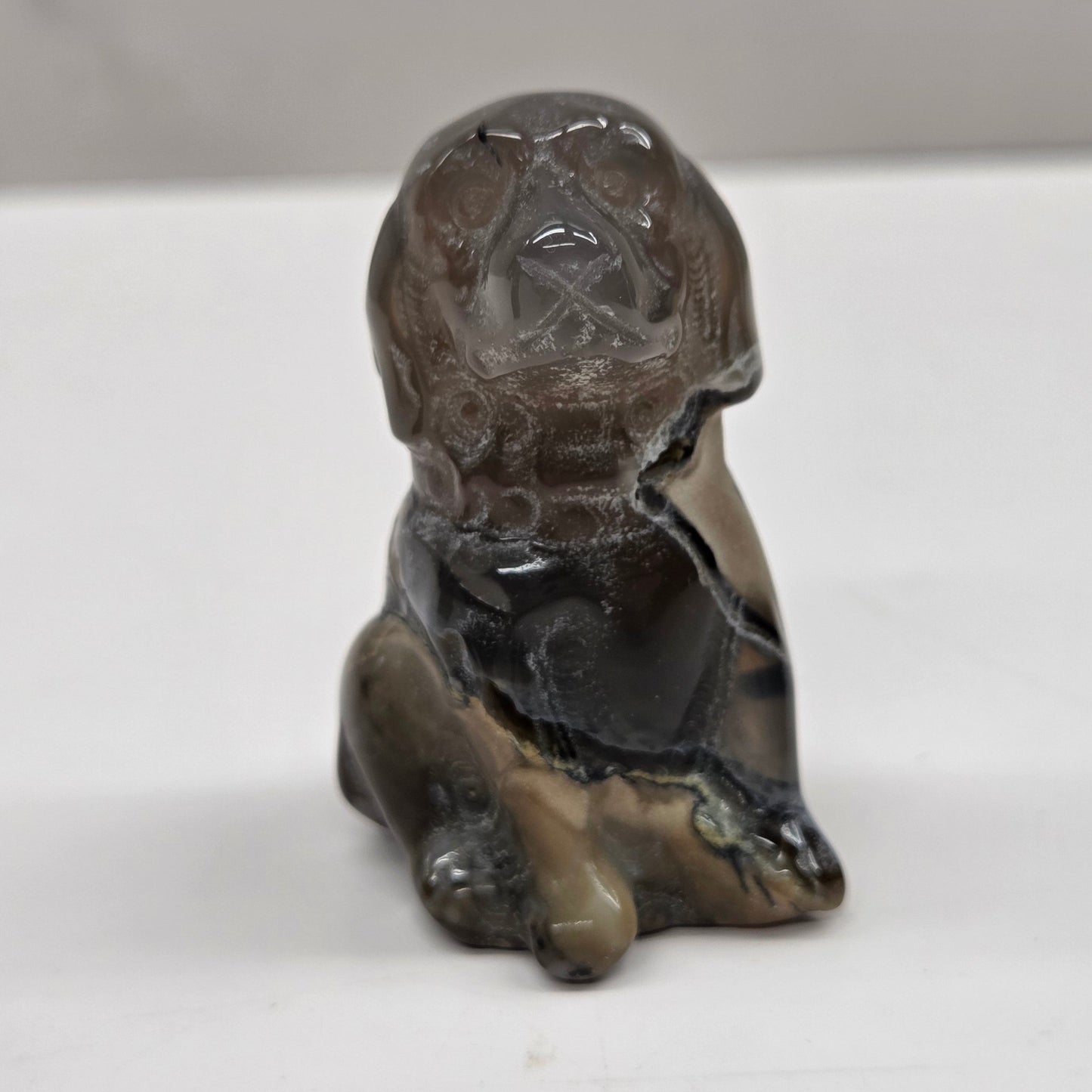 Small stone sculpture of a dog on a white surface
