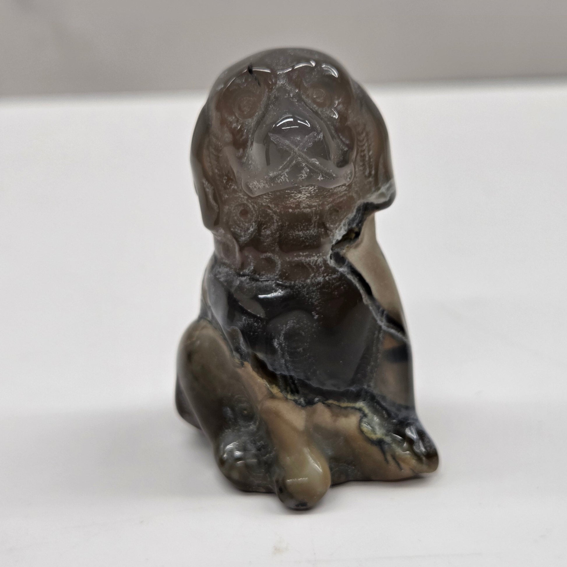 Small stone sculpture of a dog on a white surface