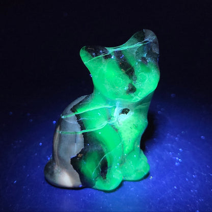 Stone cat carving under a UV lighting on a dark background