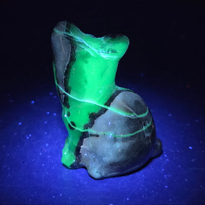 Stone cat carving under a UV lighting on a dark background