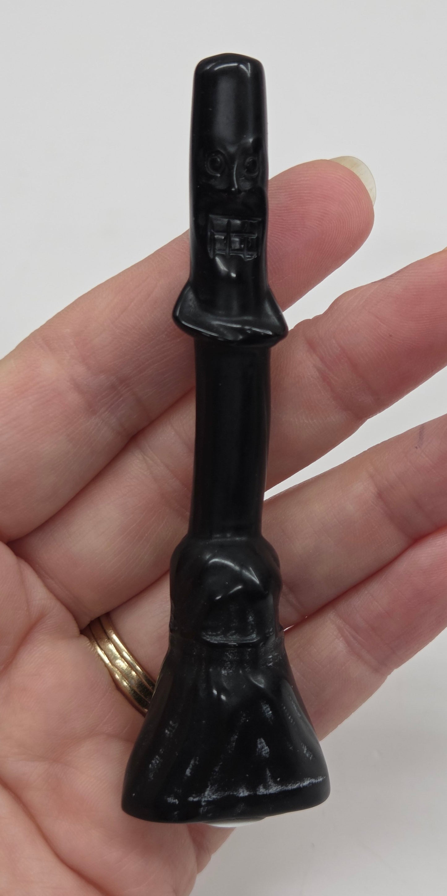 Obsidian broom carving being held in a hand