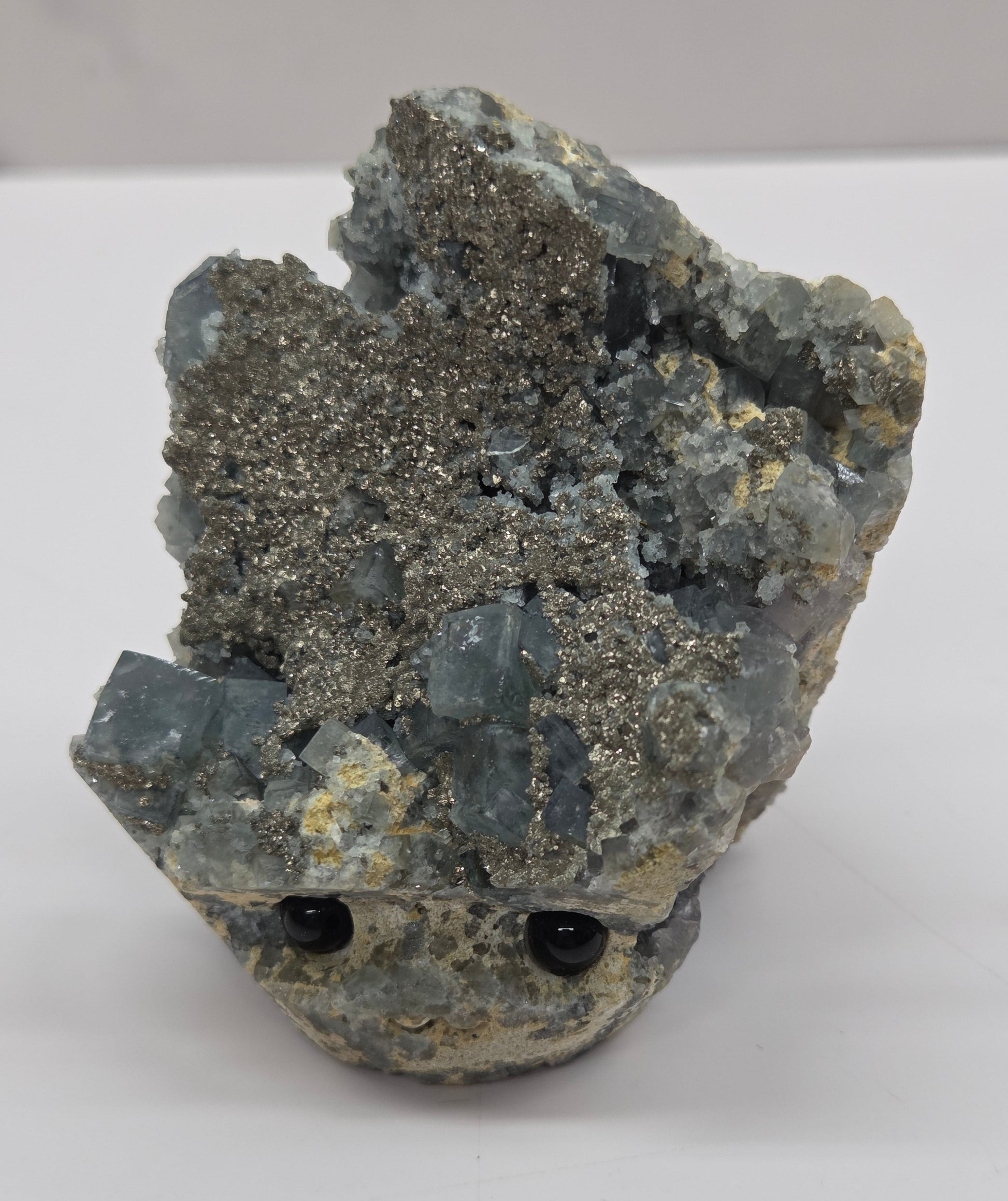 fluorite figurine with black eyes on a white surface and marble background