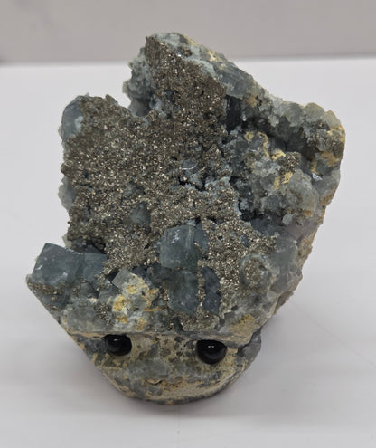 fluorite figurine with black eyes on a white surface and marble background