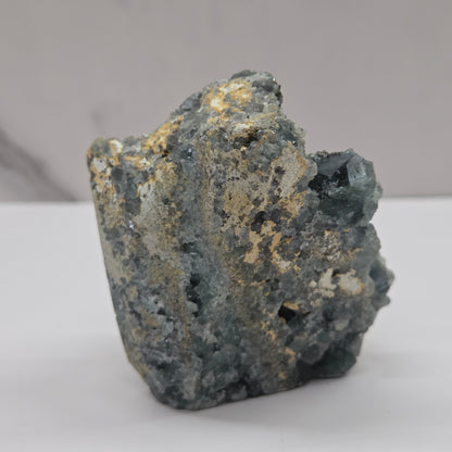 fluorite figurine with black eyes on a white surface and marble background