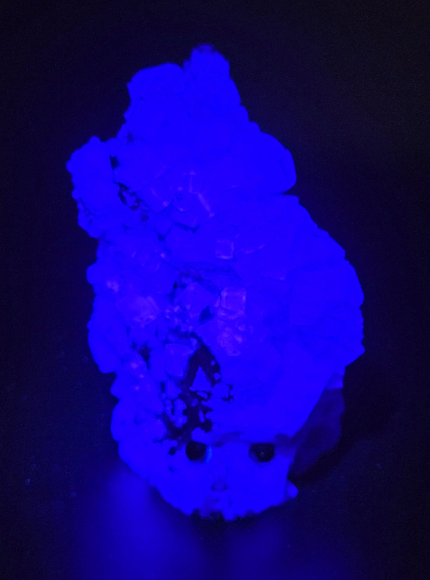 fluorite figurine with black eyes under UV light on a black background