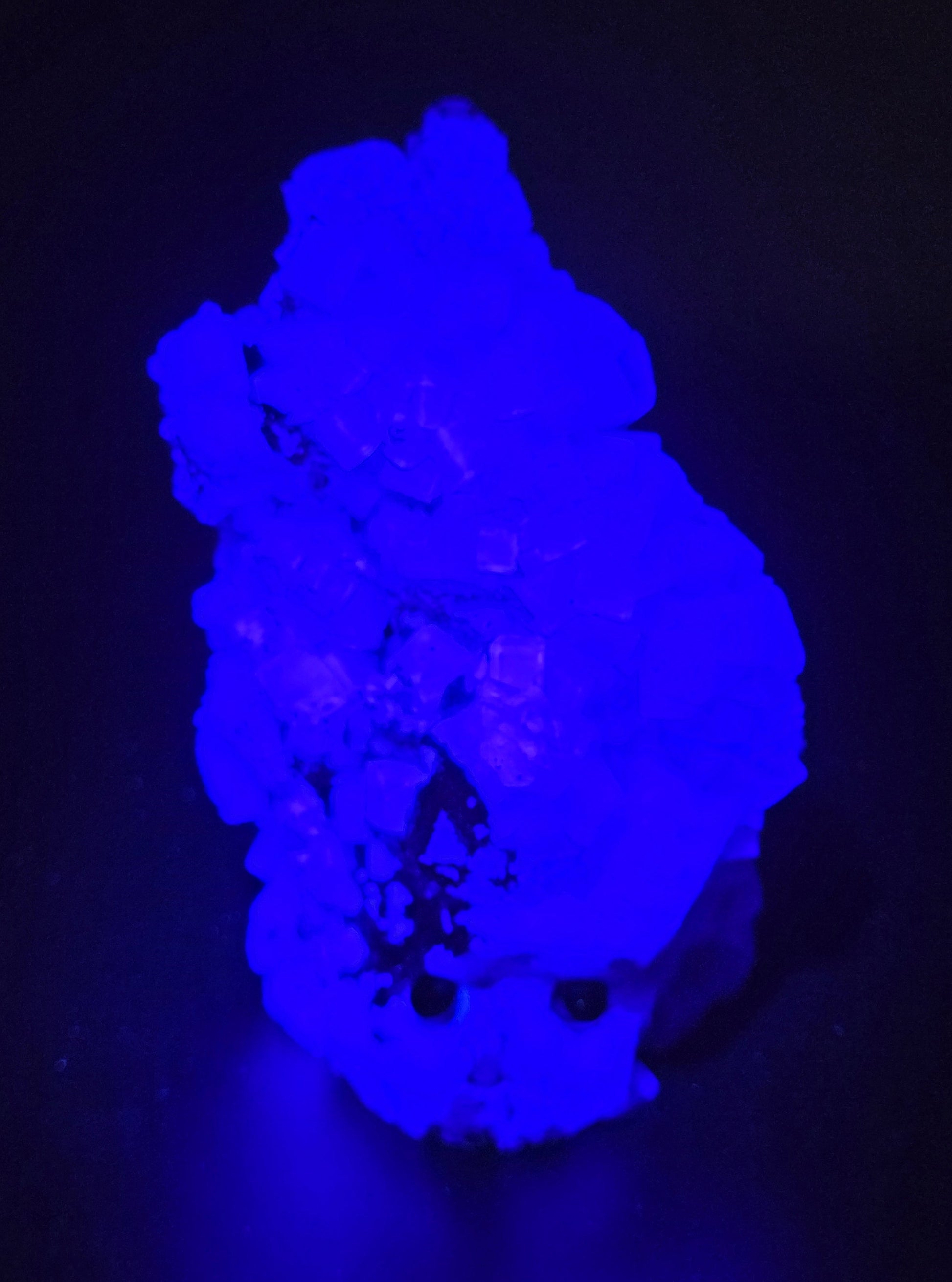 fluorite figurine with black eyes under UV light on a black background
