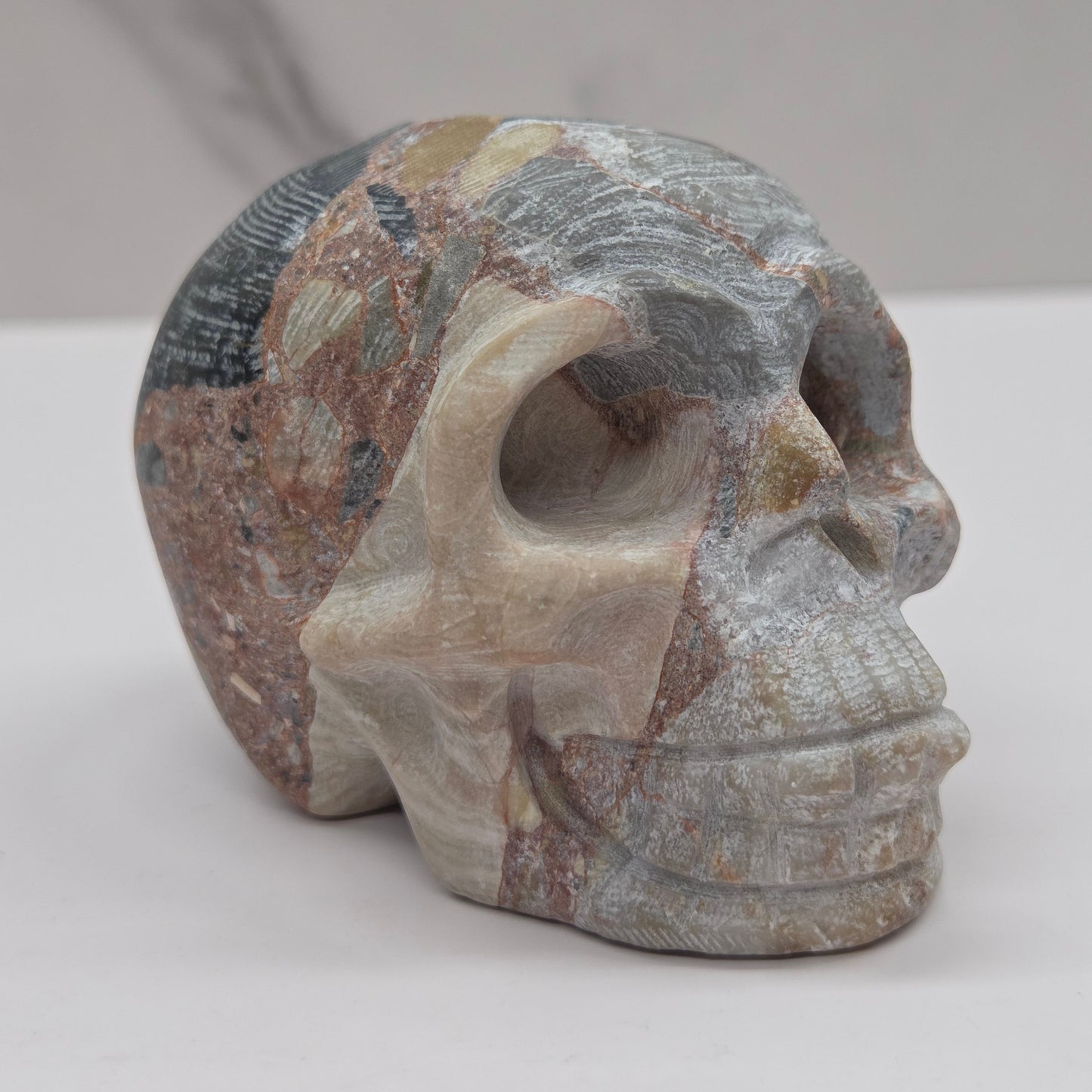 Stone skull sculpture on a white surface with a neutral background