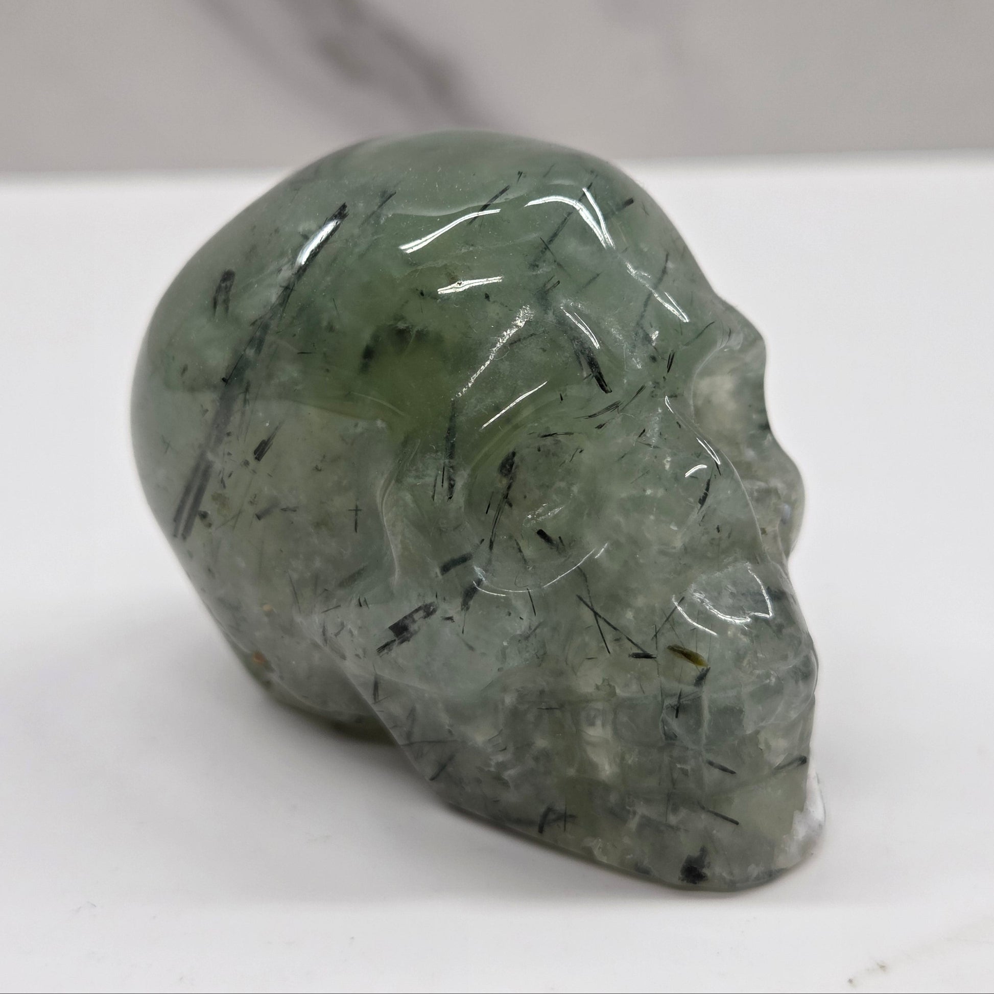 Green crystal skull on a white surface with a gray background
