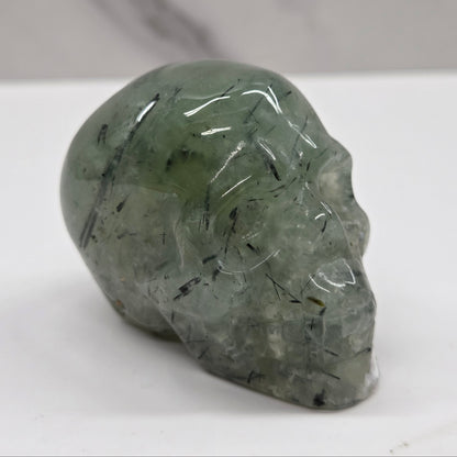 Green crystal skull on a white surface with a gray background