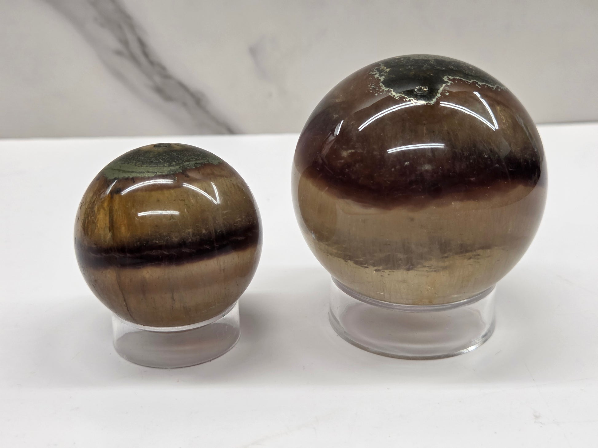 Two polished fluorite spheres on stands against a neutral background
