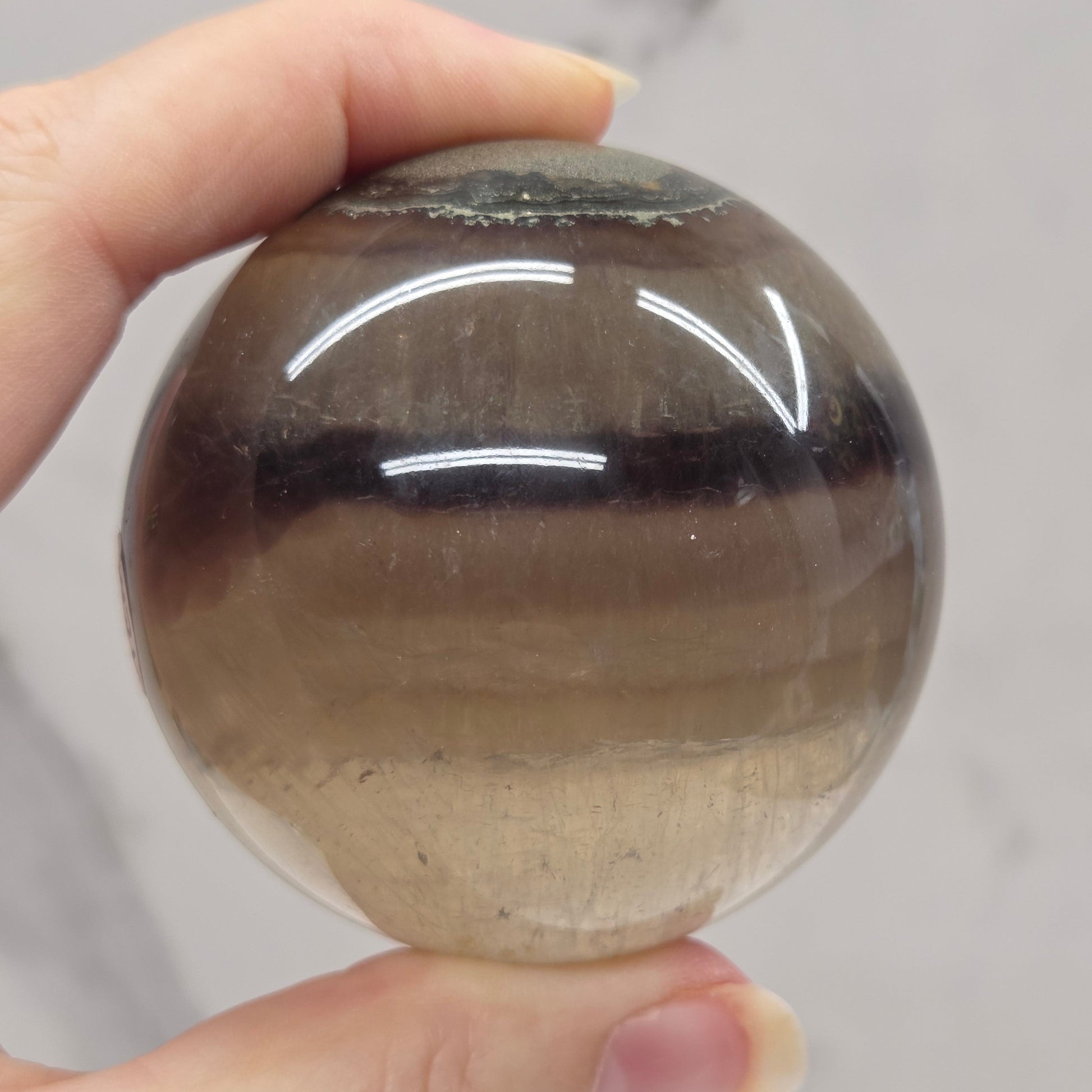 Person holding a brown and black striped crystal ball against a neutral background