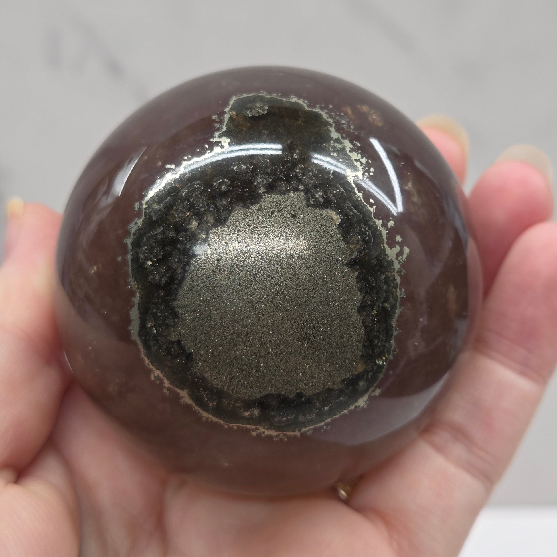 Hand holding a translucent sphere with a dark interior