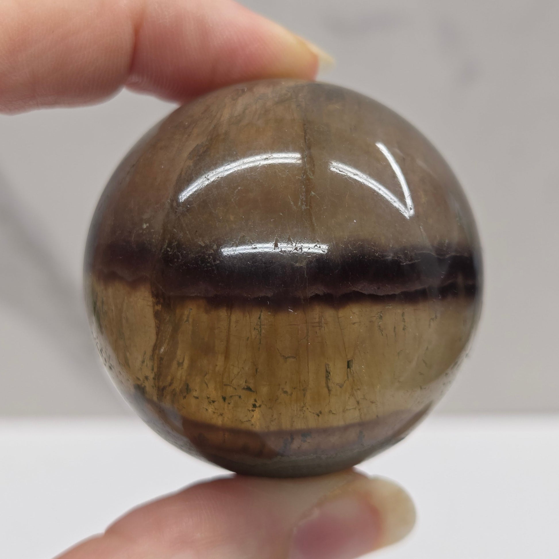 Hand holding a brown crystal ball against a neutral background