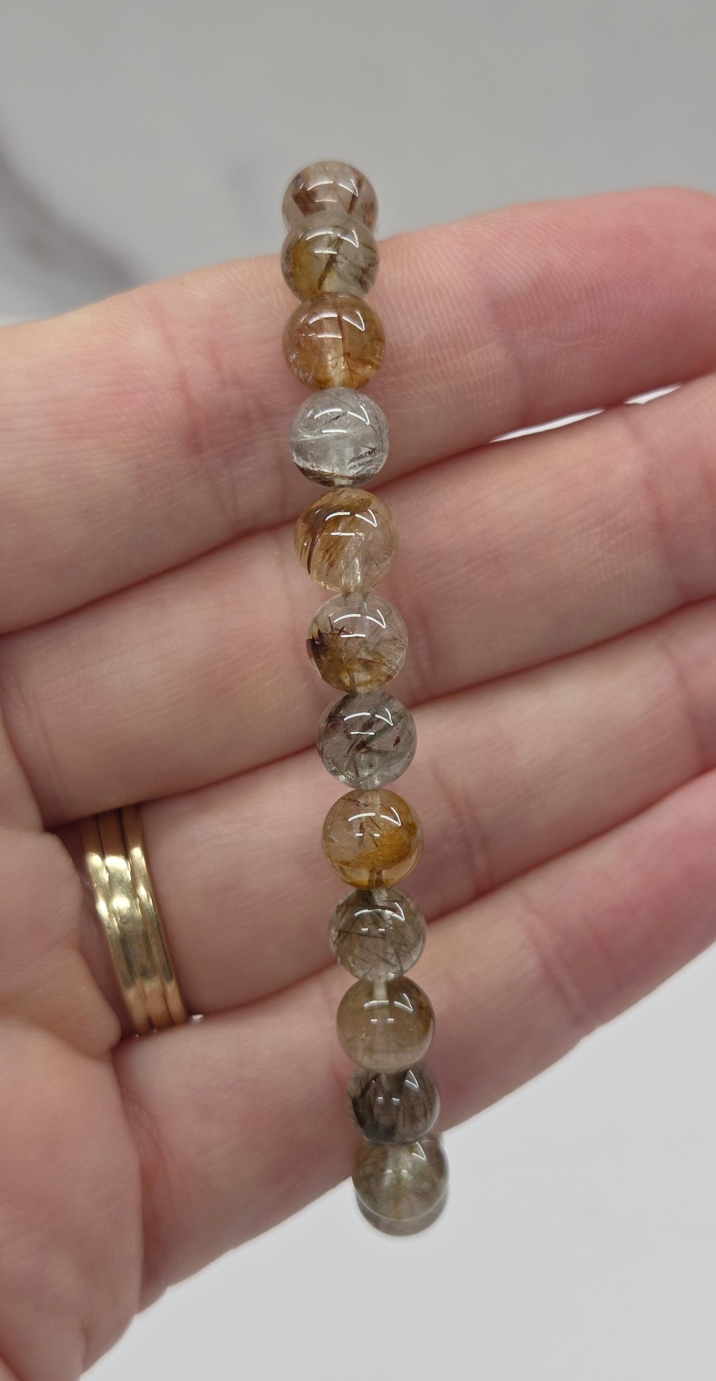 Hand holding a beaded bracelet with a plain background