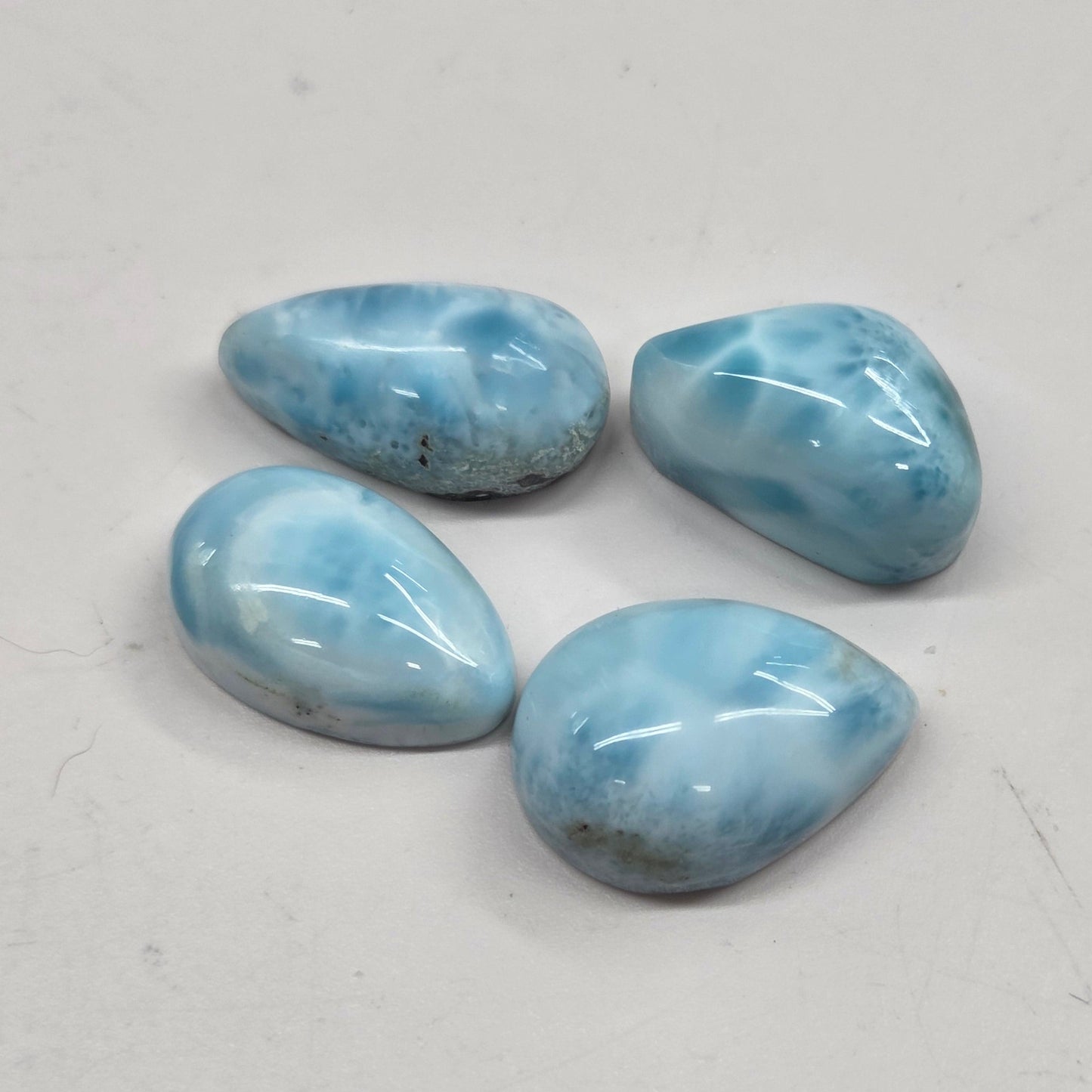 Four blue teardrop-shaped stones on a light gray background