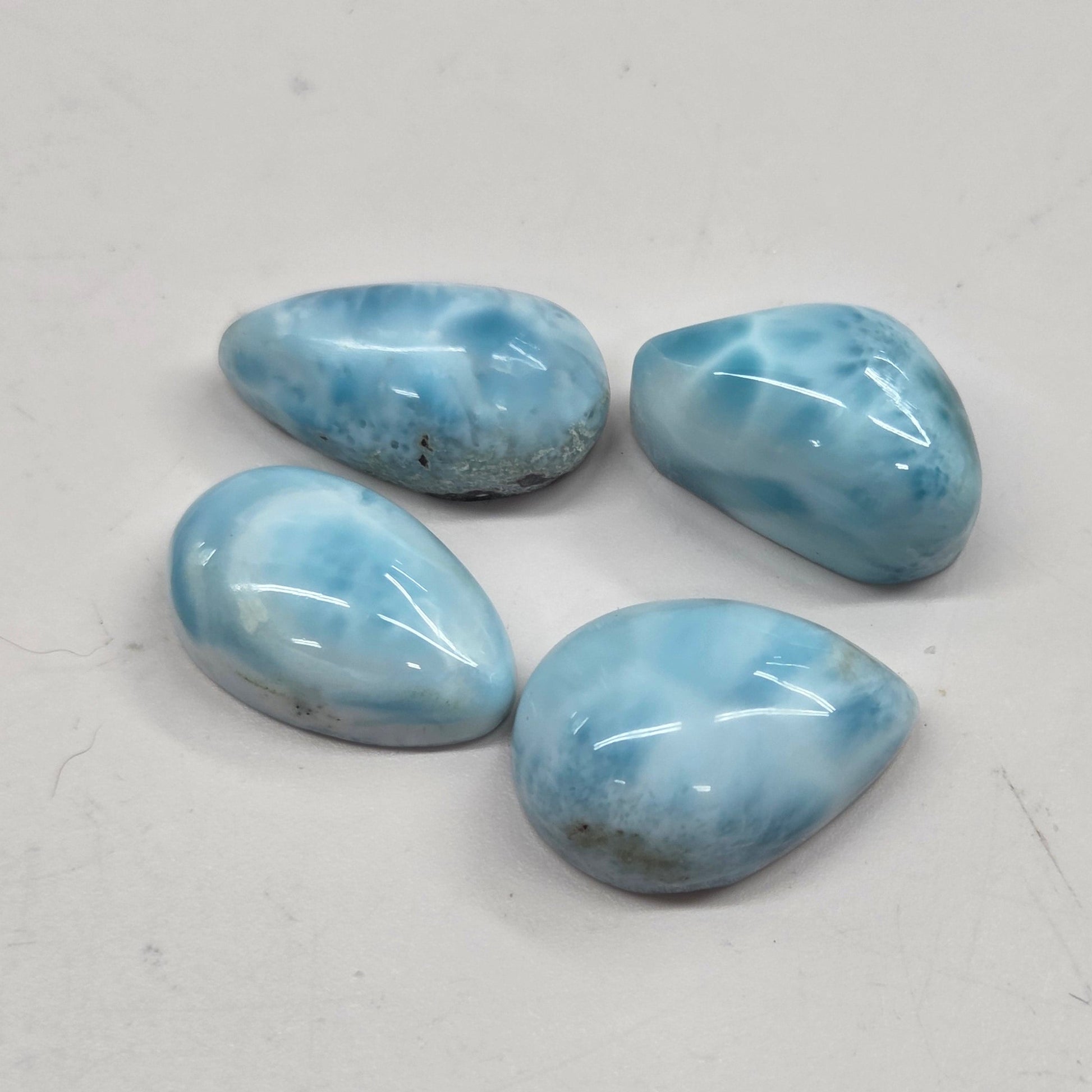 Four blue teardrop-shaped stones on a light gray background
