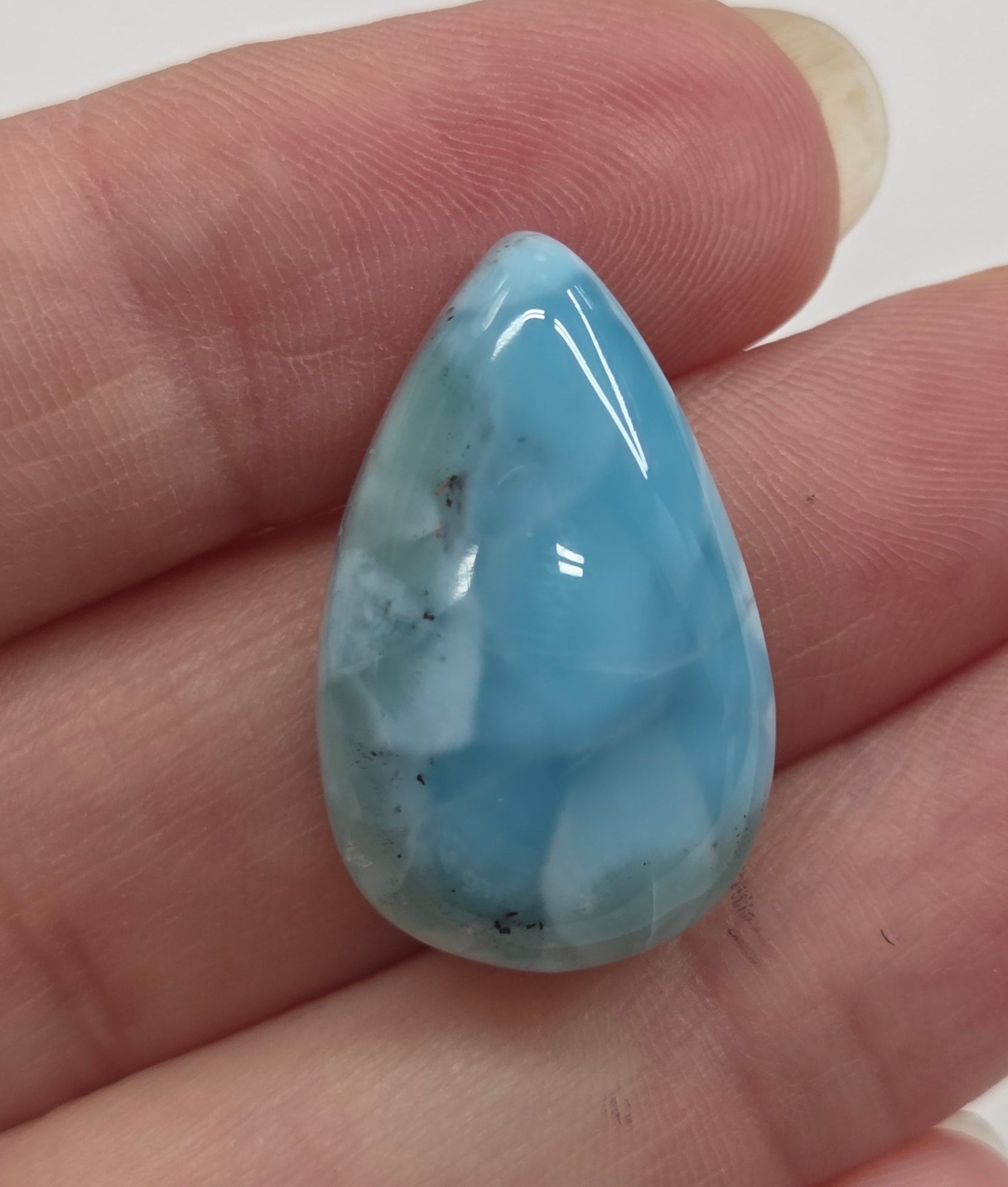 Blue marbled stone held in a hand against a white background