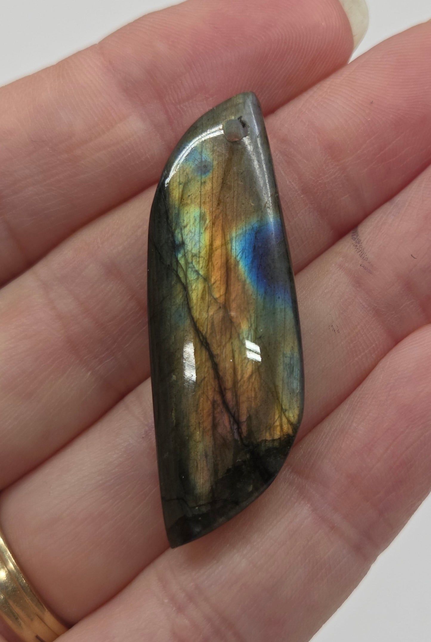 Hand holding a labradorite stone with a reflective surface