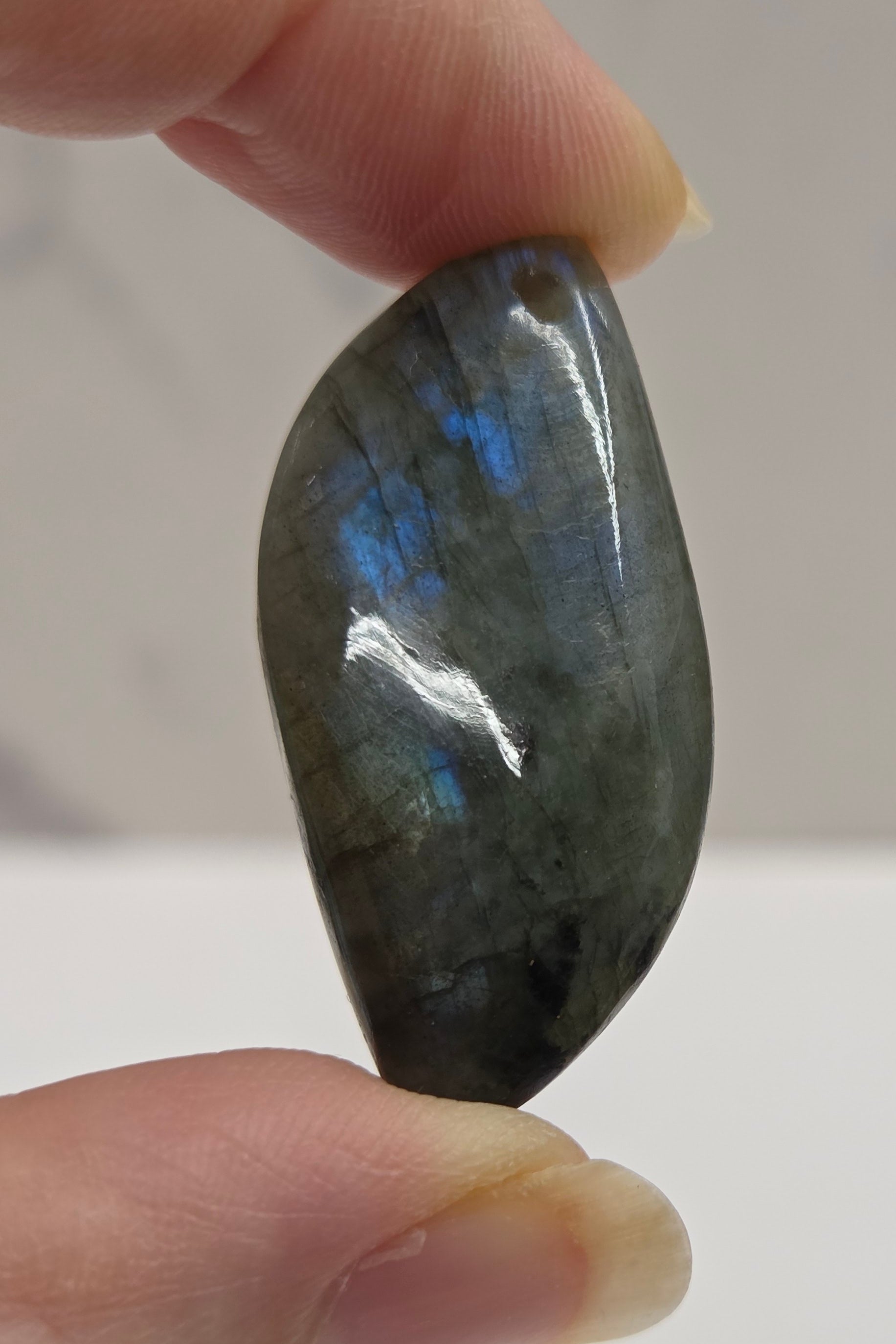 Hand holding a labradorite stone with a reflective surface