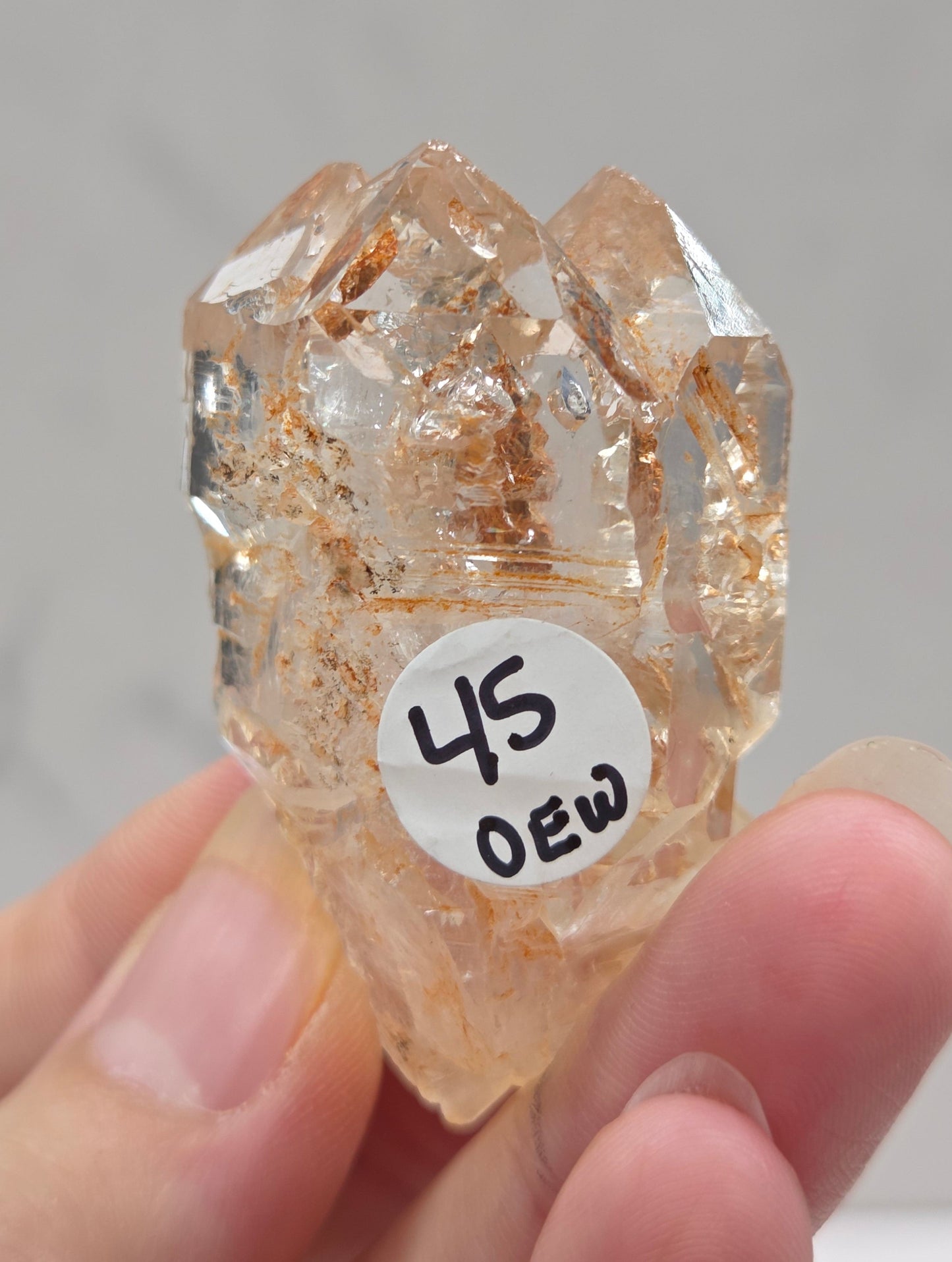 Crystal rock held by a hand with a label on a neutral background