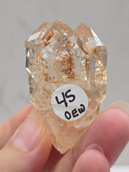 Crystal rock held by a hand with a label on a neutral background