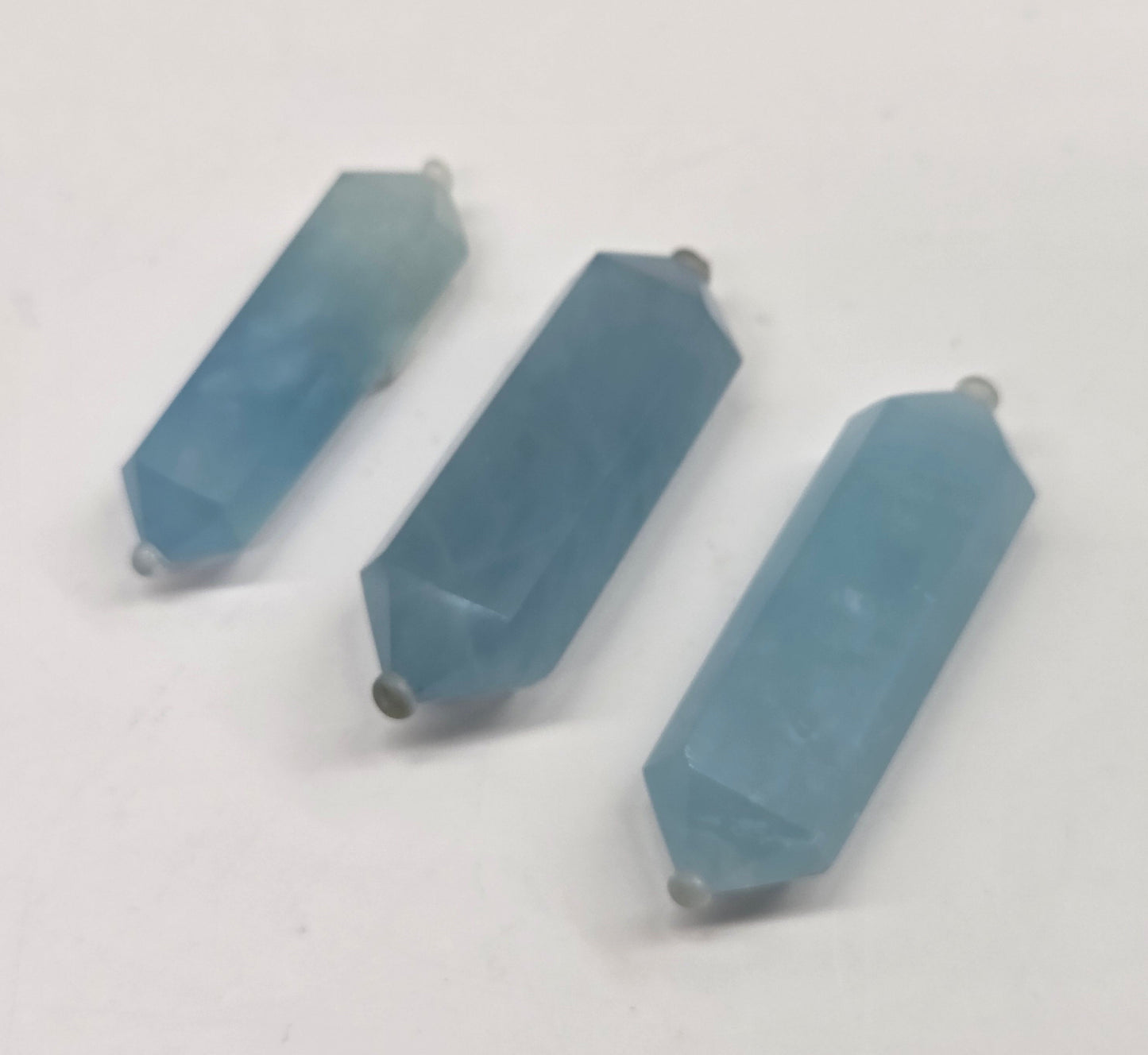Three blue aquamarine objects on a white background