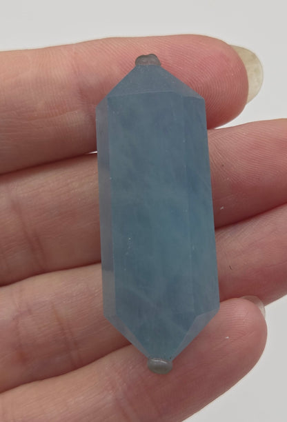 Hand holding a blue crystal against a white background