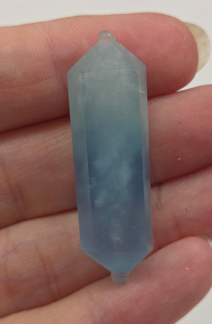Hand holding a blue crystal against a white background