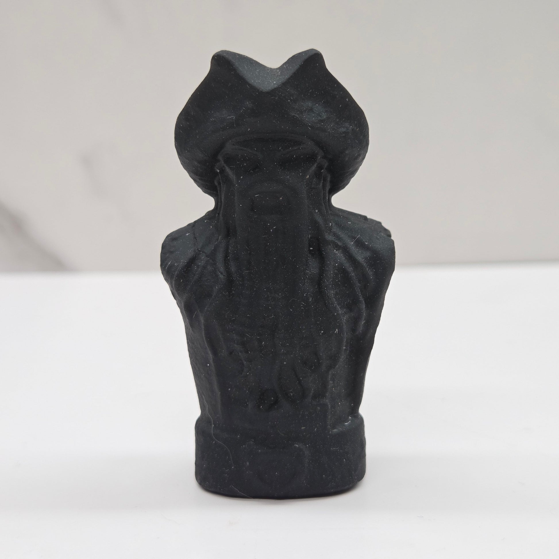 Black bust sculpture of a figure with a pirate hat on a white background