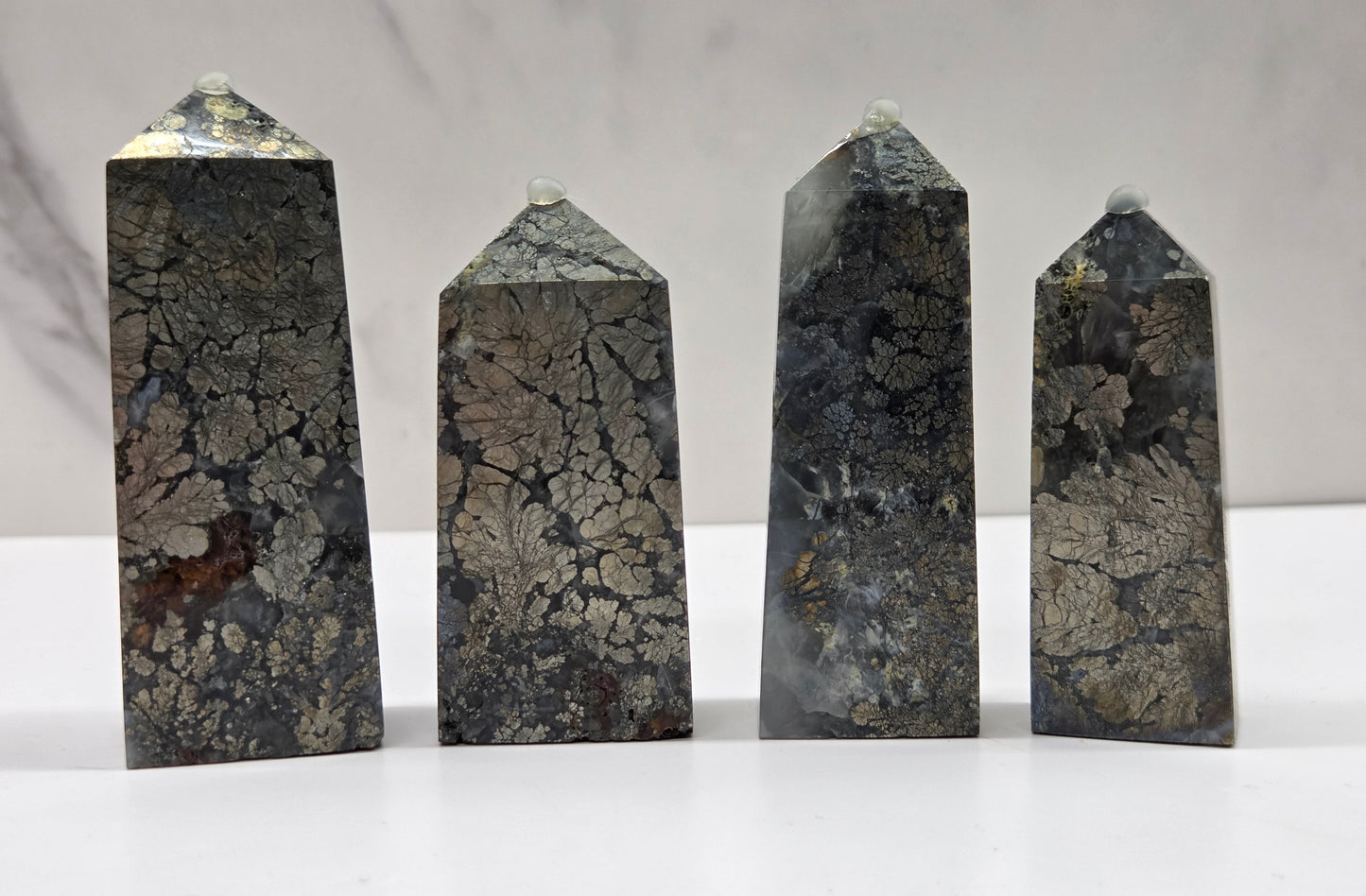 Four dark stone obelisks on a white surface with a gray background